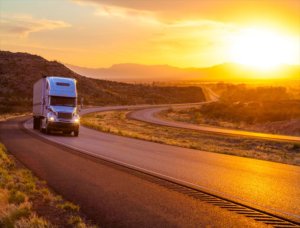 image of white semi driving away from the sunset
