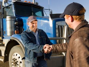 image of truck drivers shaking hands in front of blue semi