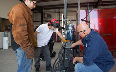 Image of two students and instructor working in welding lab