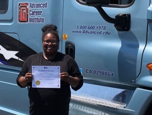 image of ACI graduate holding certificate in front of blue truck
