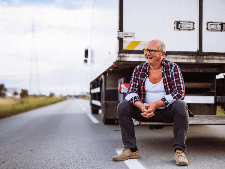 image of man sitting on step at the back of a white semi-truck