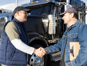 Image of truck drivers shaking hands in front of black semi