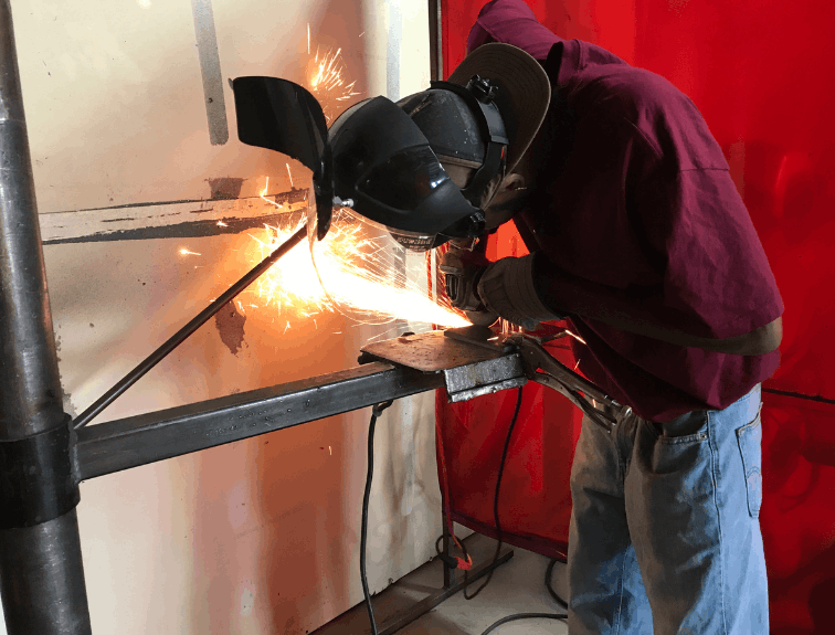 Side view of a welder welding, sparks flying