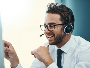 A Help Desk Technician smiling and looking at computer screen
